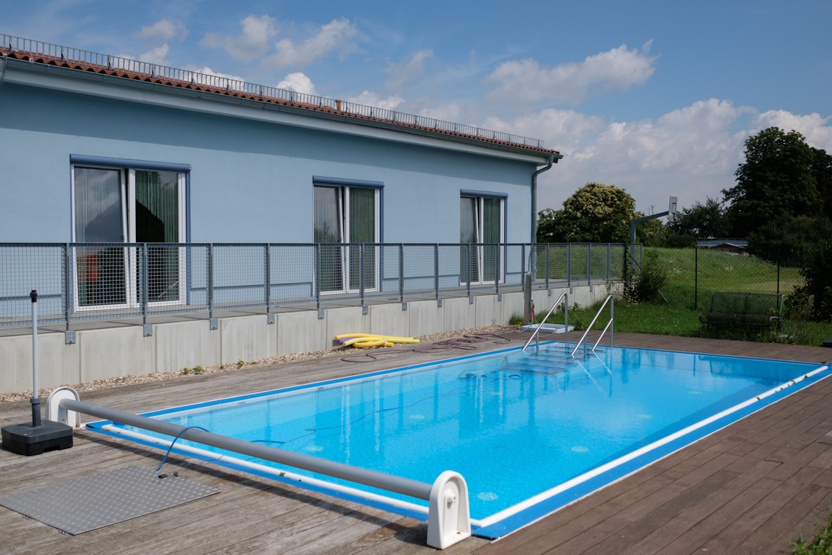 Das einstöckige Gebäude der Fördergruppe 2. Im Vordergrund sieht man das Schwimmbecken der Fördergruppe.