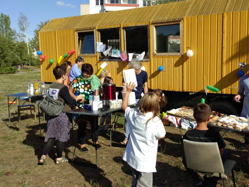 Bauwagen mit Menschen, Kuchen und Ballons