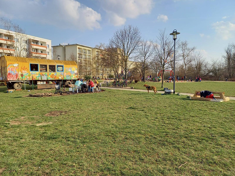Bauwagen im Park mit Menschen am Tisch