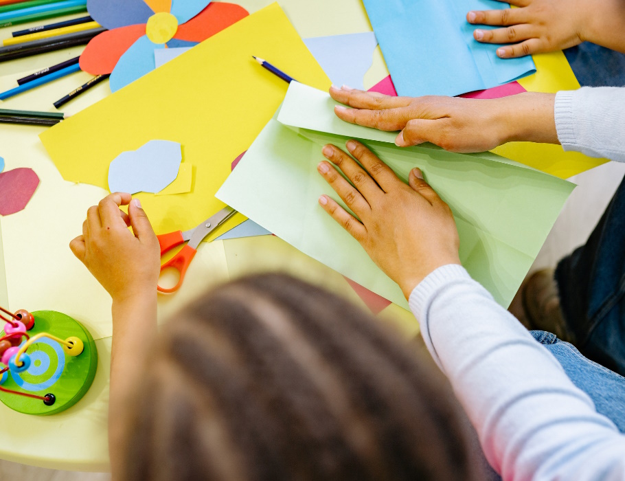 Bastelnde Kinder von oben mit buntem Papier