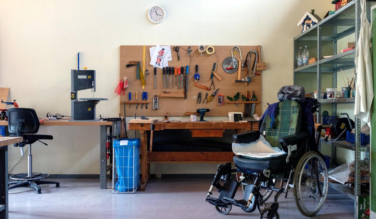 Werkzeugbank im Hintergund, davor steht ein Rollstuhl
